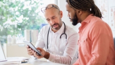 Healthcare provider sitting with a patient and showing them a tablet