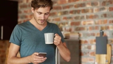 Person holding a cellphone and a cup of coffee
