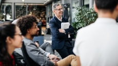 Numerous people sitting in a circle looking at something offscreen