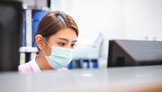 A nurse wearing a surgical mask working at reception