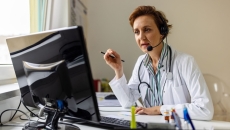 A doctor uses headphones with a mic in a call 