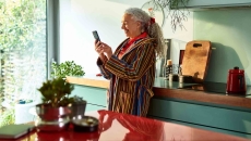 Person standing in their kitchen looking at the phone