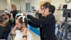 A therapist-in-training putting on the SynPhNe device on a volunteer's head