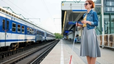Blind person standing on a train station platform