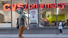 A person wearing a mask walking by a CVS pharmacy