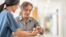 Healthcare provider standing up and talking to a patient who is also standing