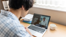 A person video chatting with a doctor on a laptop.