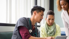 Healthcare professional discusses with two people over a laptop