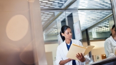Person in lab coat looking down at file