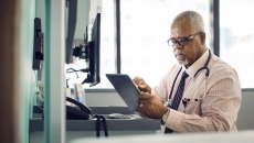 Healthcare provider at a desk scrolling through a tablet