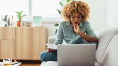 Person sitting on their couch while looking at a computer