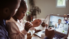 Two people conferring with a healthcare professional via a laptop computer