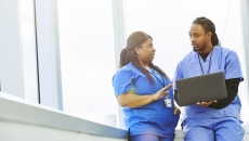 Healthcare professionals conferring while using a laptop computer