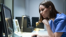 A doctor looking at a MRI results on a desktop computer