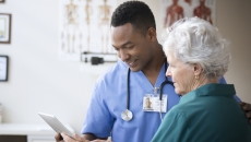 A doctor and a patient look at a tablet in his office.
