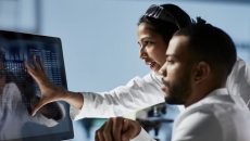 Doctors looking at patient data on a monitor