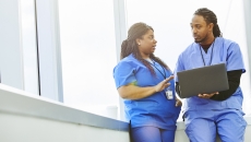 A doctor showing his colleague information on a laptop