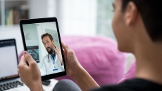 Person holding a tablet while talking to a telehealth provider