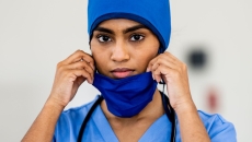 Doctor wearing blue scrubs and holding their face mask