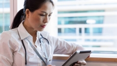 Healthcare provider looking at a tablet while sitting next to a window