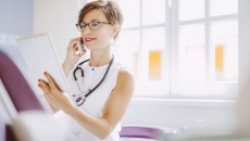 Healthcare provider wearing a white shirt and looking at a tablet