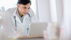 A doctor using a laptop to write referrals