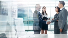 Four people standing a room with two of them shaking hands