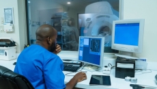 Healthcare provider sitting in a diagnostic imaging room with an MRI machine in the window