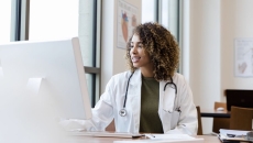 A doctor reviewing a patient record on a desktop computer