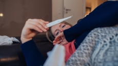 A sick person looking at a thermometer