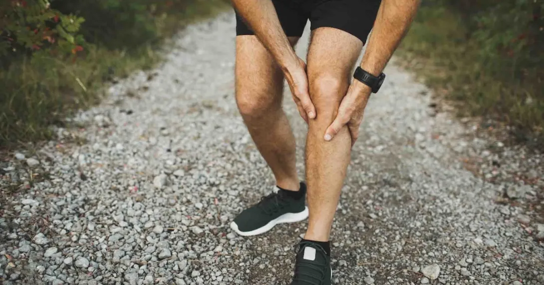Person holding onto their leg while in the wilderness