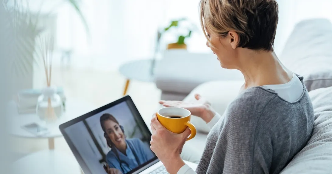 Woman interacting with healthcare professional via laptop 