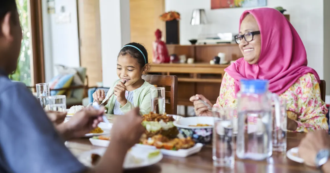 People sitting around a dining room table eating a meal