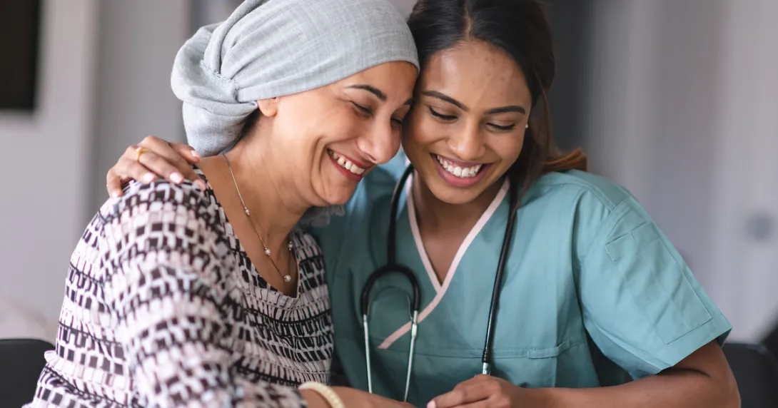 Two people sitting next to each other, one wearing a scarf on their head and the other in scrubs