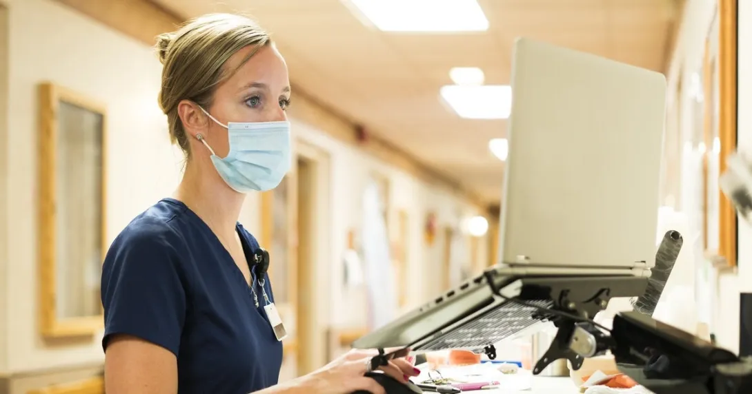Healthcare worker in mask working on a laptop