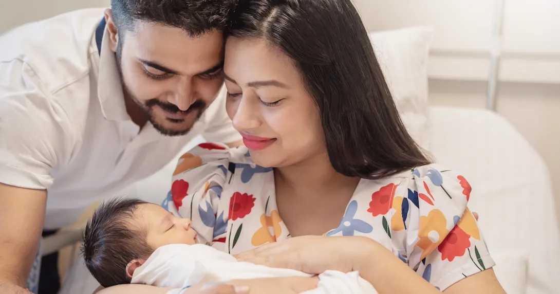 Two people sitting in a bed holding another person