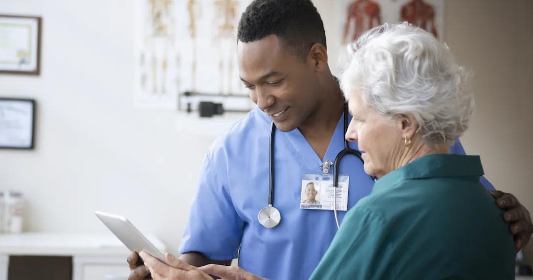 Healthcare provider and a patient standing next to each other both looking at a tablet