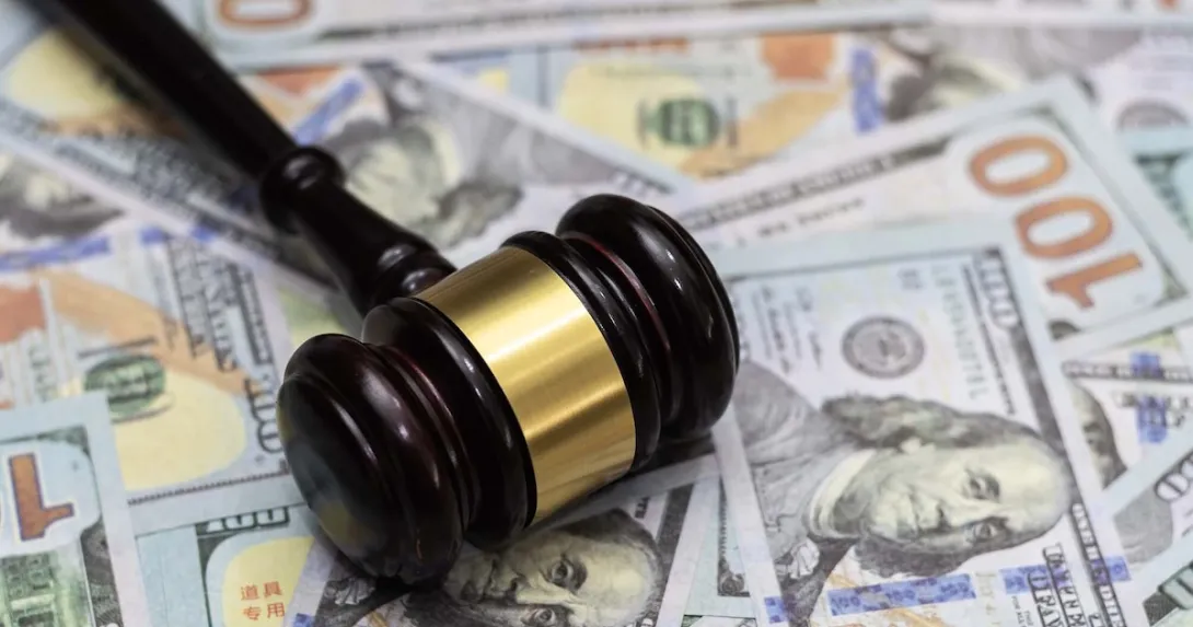 A gavel lying on a pile of $100 bills