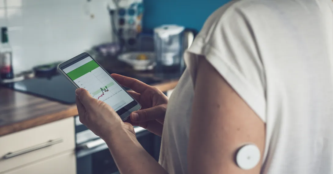 A person wearing CGM tracking blood glucose data on a smartphone