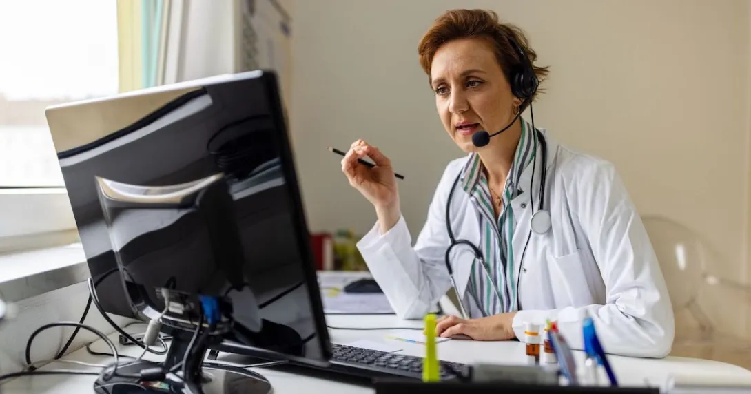 A doctor wearing a headset and working on a computer