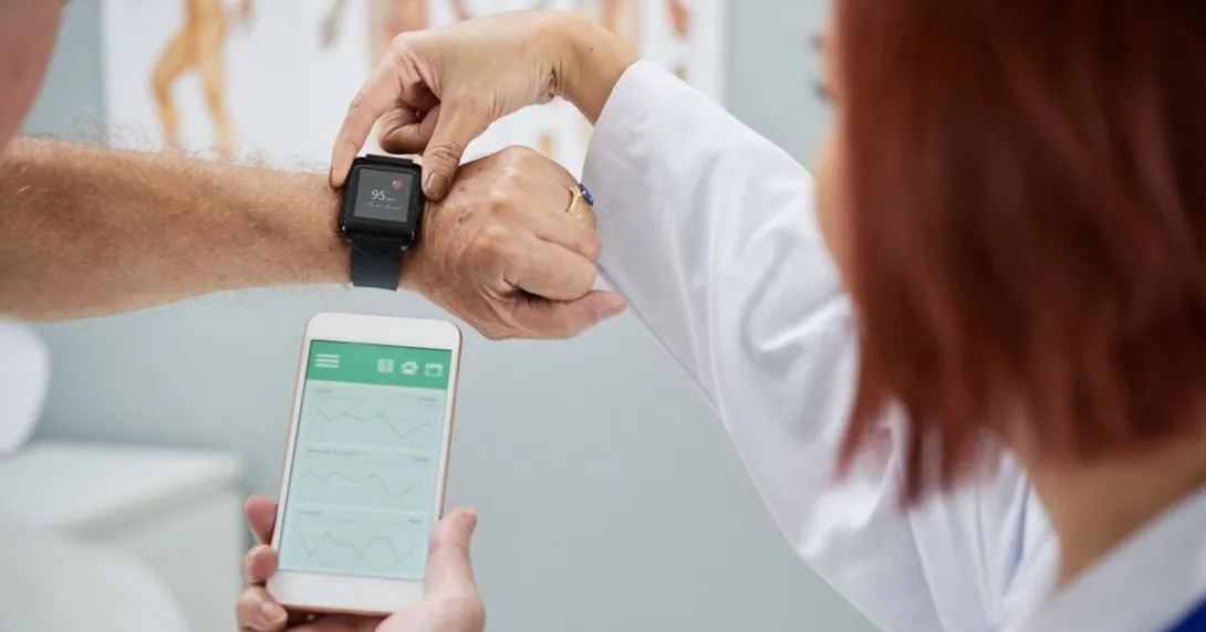 A doctor helping a patient synchronize heart rate data on a smart watch and phone