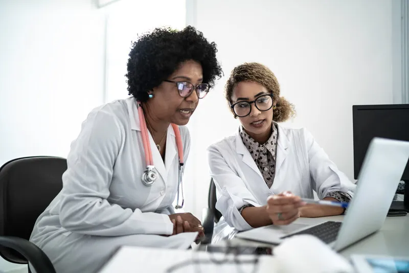 Doctors using a laptop to join a digital conference.
