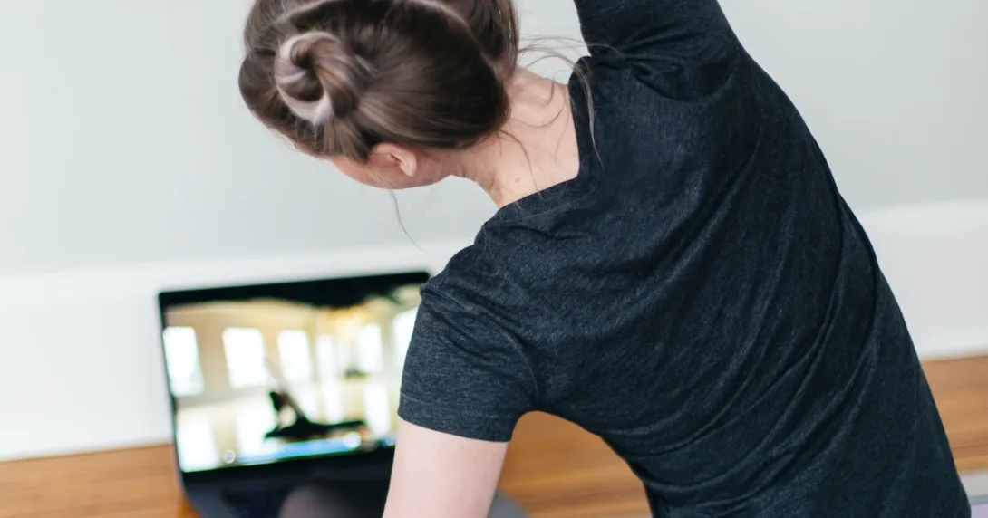 A person following a video stretch routine on their laptop