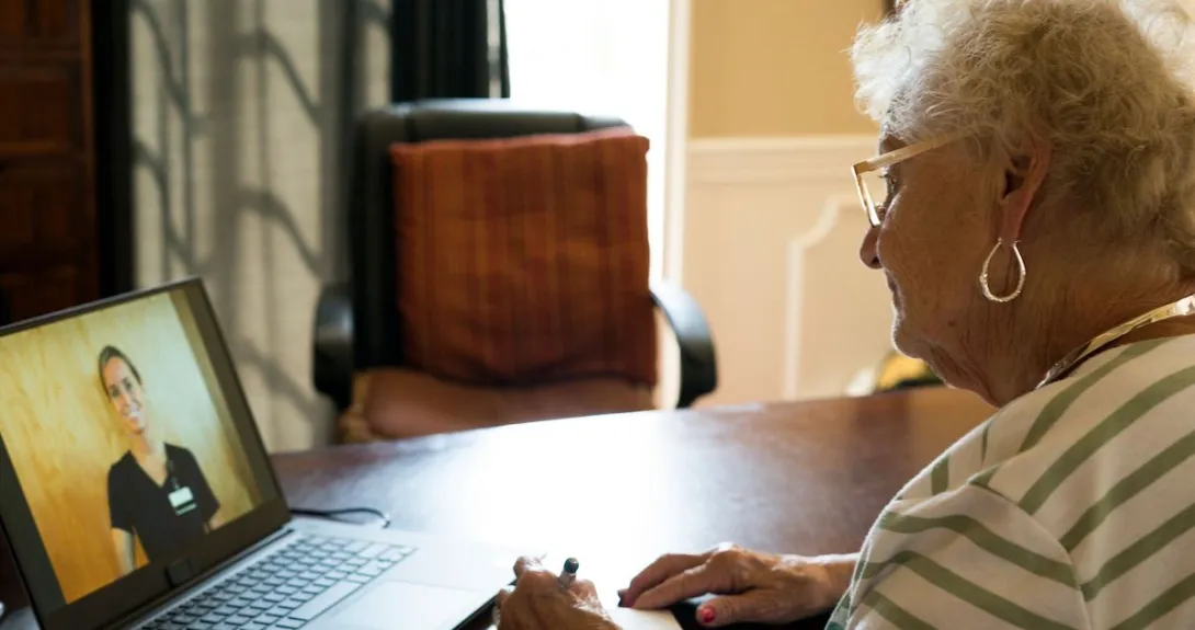 An older woman talking to a provider through a video call on her laptop