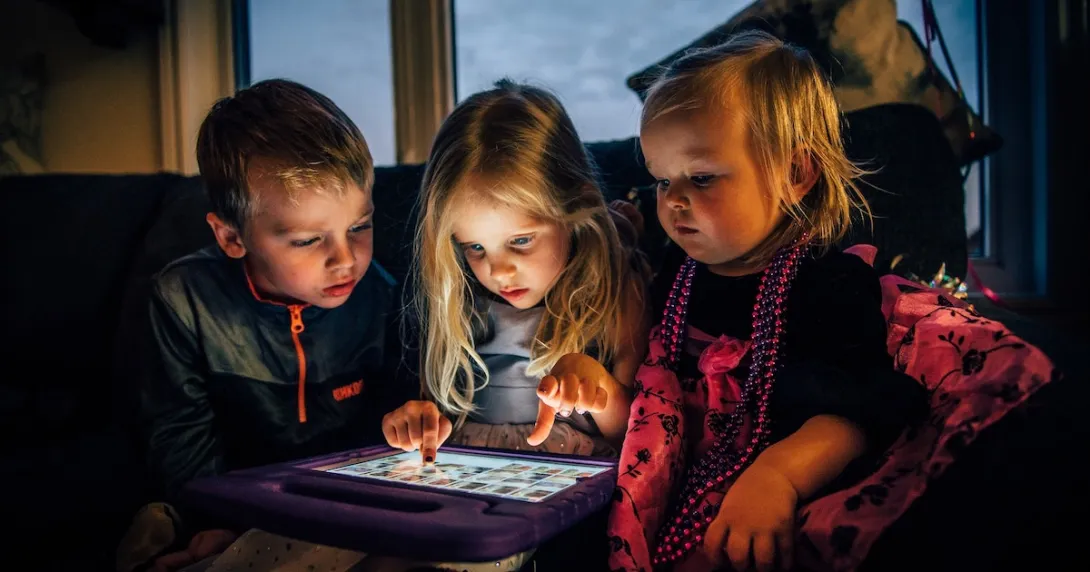 Three children playing on a digital tablet