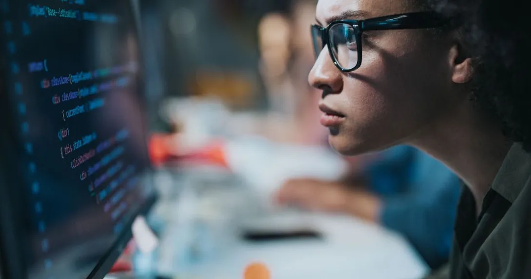 A focused programmer looking at her computer screen
