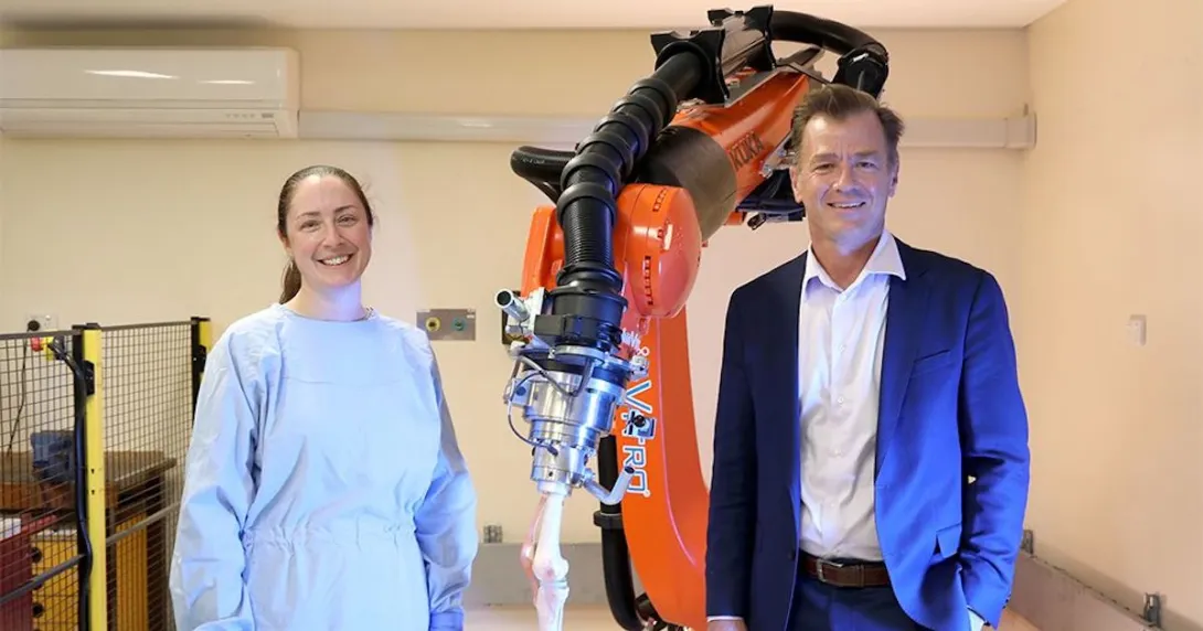 University of Sydney professors Elizabeth Clarke and Bill Walter pose beside the robotic arm KOBRA