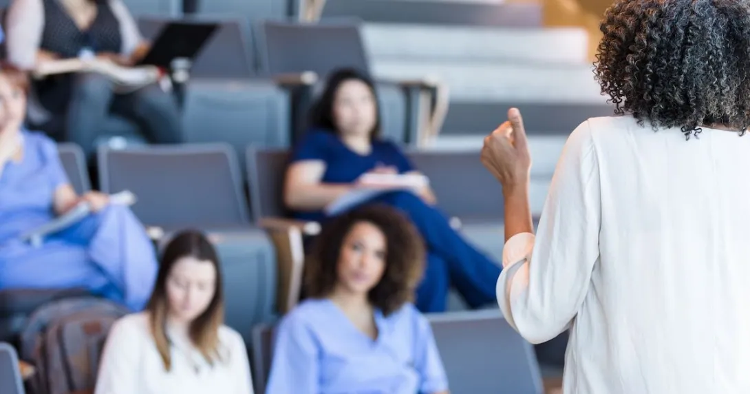 Students in scrubs sitting in a classroom looking at a teacher