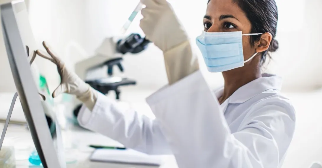 Person wearing mask holding test tube