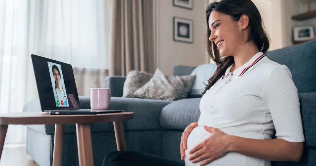 Pregnant person sitting on the floor looking at a computer